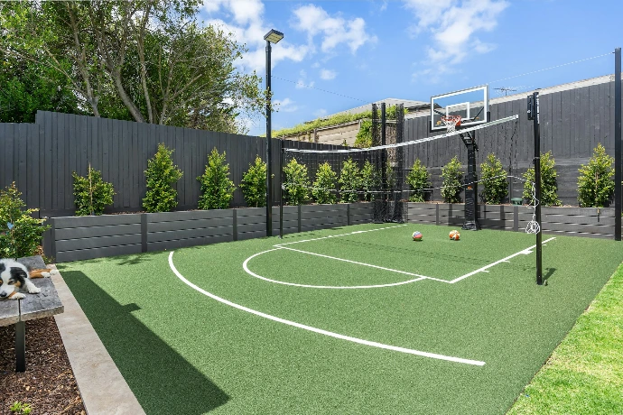 A backyard with a basketball court and basketball hoop